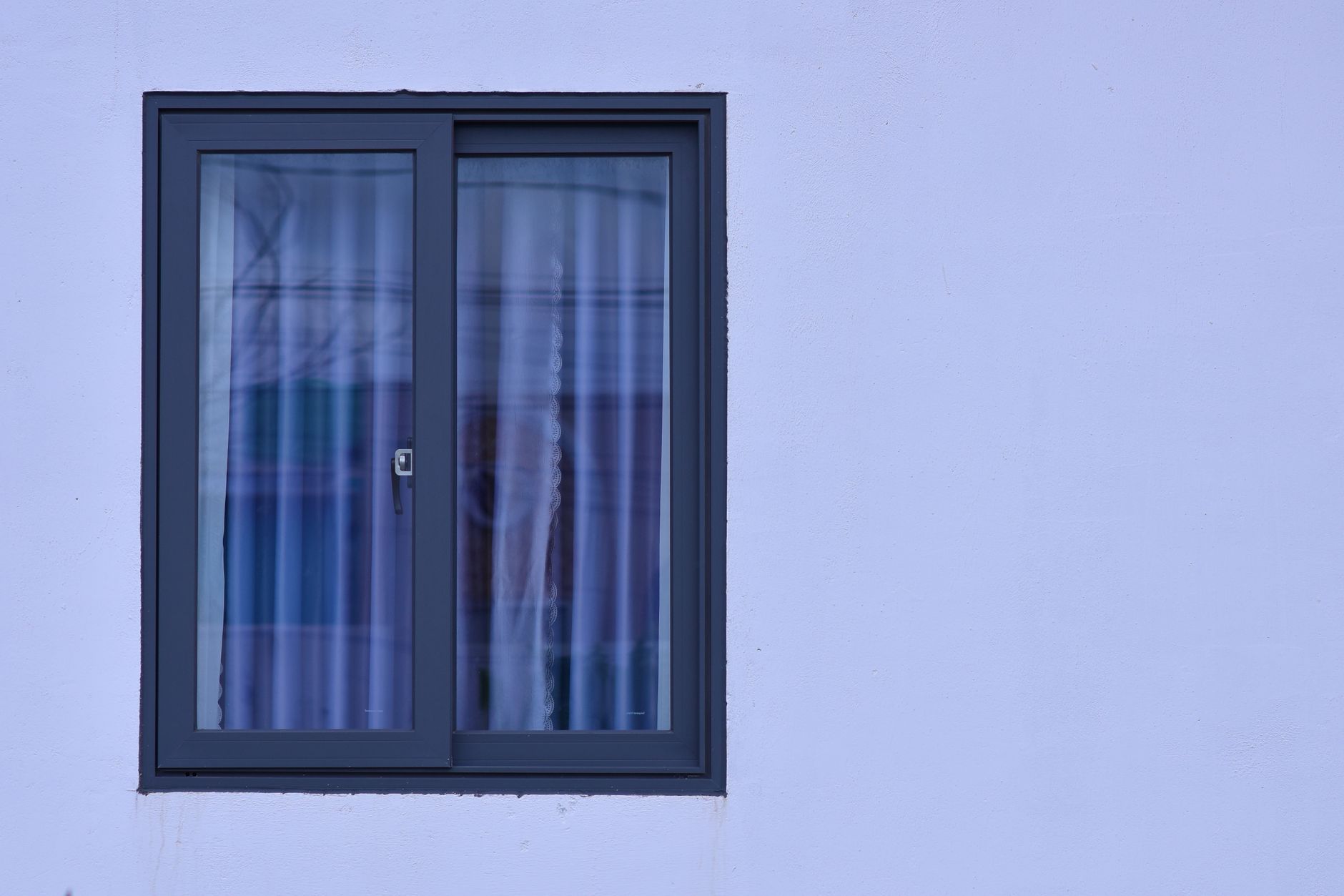 A minimalist view of a modern window with frosted glass on a light blue wall in Riverside, CA