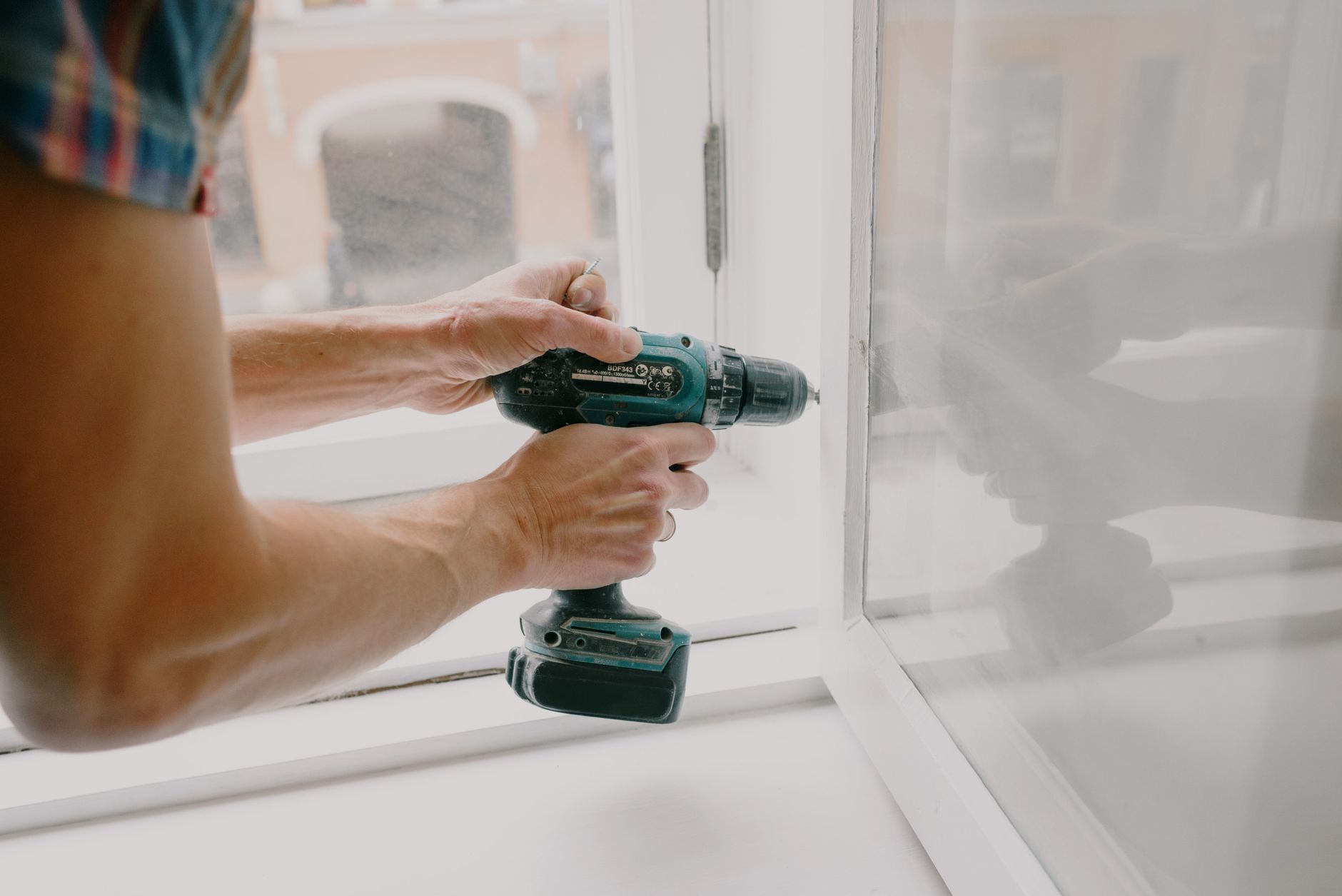 Side view of crop anonymous male mechanic fixing window with screwdriver during renovation process in in Riverside, CA